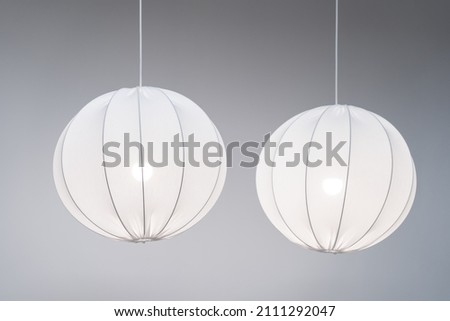 Two white modern pendant lamps, fabric spherical chandeliers in Scandinavian style on grey background