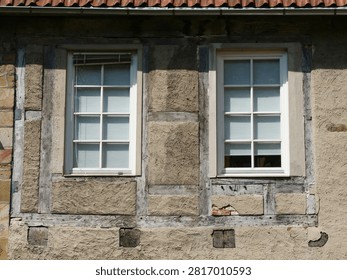 Two white, multi-pane lattice windows set into a historic half-timbered facade with clay or stucco infill