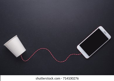 Two White Paper Cup Connect With Red Rope Used For Classic Phone And Modern Smartphone On Black Stone Table Board Background. For Compare The Old And New Communication System Concept