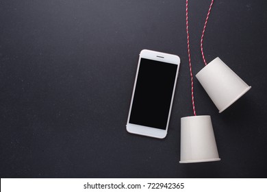 Two White Paper Cup Connect With Red Rope Used For Classic Phone And Modern Smartphone On Black Stone Table Board Background. For Compare The Old And New Communication System Concept