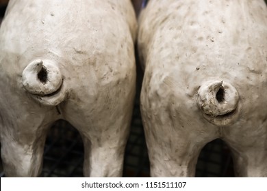 Two white pig tails - view of two pig statue back ends with wiggly tails - selective focus