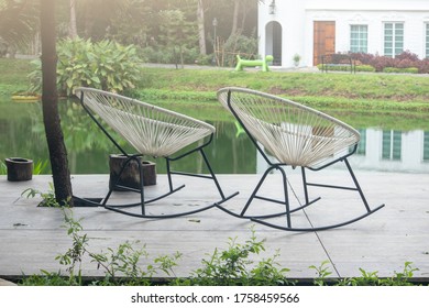 Two White Rocking Chair On The Backyard In Tropical Garden Near Lake,two Empty White Rocking Chair,there Are No People Around.Spring Morning By The Lake,The Concept Of Loneliness, Relaxation.