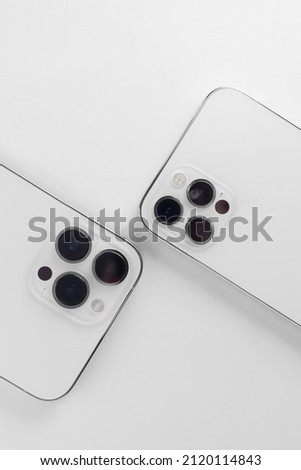 two white smartphones on a white background lie with the cameras up