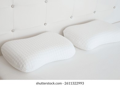 Two white soft memory foam pillows on mattress. Closeup.