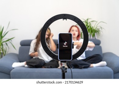 Two White Teenage Girls Shoot A Viral Video On Their Channel In The Social Network Tiktok At Home On The Couch. The Phone Is Mounted On A Tripod Ring Lamp. Turkey, Istanbul, June 17, 2022