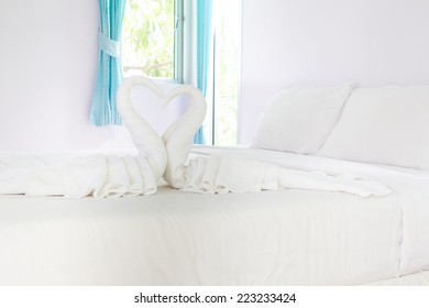 Two White Towels Swans On Bed Sheet In Hotel Room  