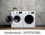 Two White Washing Machines Against a Concrete Wall