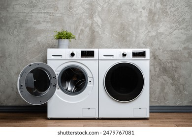Two White Washing Machines Against a Concrete Wall