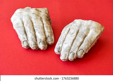 Two White Weathered Broken Hands Of A Stone Statue On A Red Background. Iconoclasm Concept.