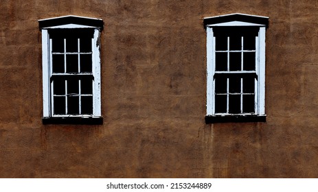 Two White Windows In A Pueblo Style Wall