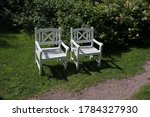Two white wooden chairs in the park.