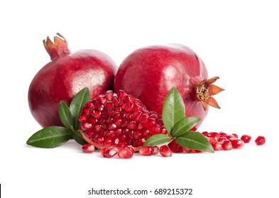 two whole and part of a pomegranate with pomegranate seeds and leaves isolated on white background