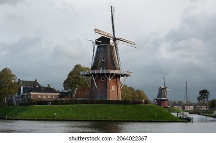 Two windmills on the bulwark of the old city Dokkum in the Netherlands on a dark and drizzly day in autumn - Shutterstock ID 2064022367