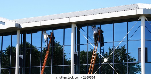 Two Window Cleaners At Work On Office Building