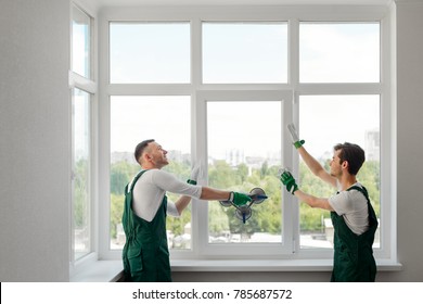 Two window installers. Positive mood and good job of young workers replacing a window in the living room. - Shutterstock ID 785687572