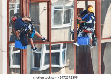 Two window washers cleaning the windows of a high-rise building