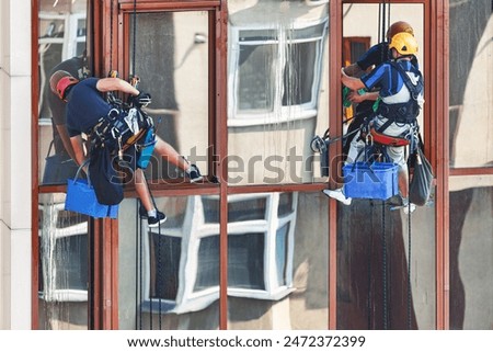 Two window washers cleaning the windows of a high-rise building