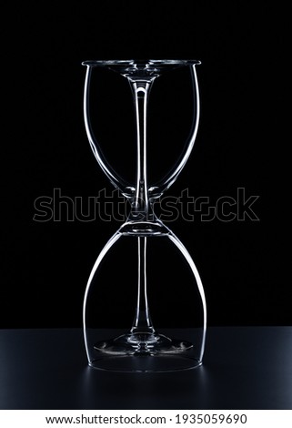 Two wine glasses on a black background with an outline outline are depicted in the form of an hourglass