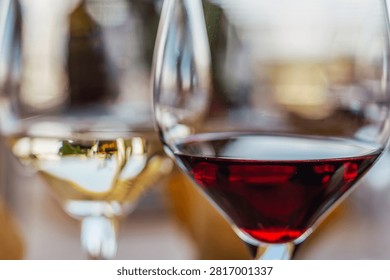 Two wine glasses placed side by side containing white wine and red wine on a table. The pair of glasses evokes comparative tasting, food pairing, and oenology. Natural light enhancing the wine colours. Versatile image for wineries, restaurants, and gastronomy events.