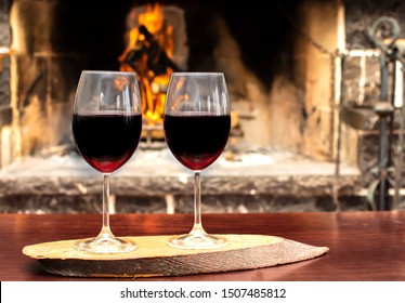 Two Wineglass Of Red Wine In Front Cozy And Warm Fireplace, In Country House. Winter Or Autumn (fall) Vacation. Happy New Year, Merry Christmas Or Saint Valentine's Day. Romantic Evening For Couple.