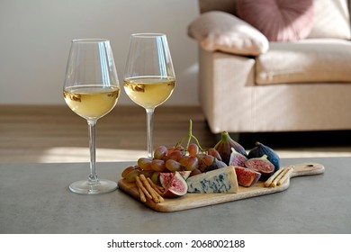 Two wineglasses of vintage chardonnay with delicious appetizers. Couple of glasses of white wine, italian breadsticks, figs and grapes. Interior background. Close up, copy space. - Shutterstock ID 2068002188