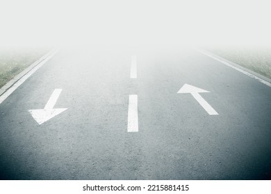 Two wite arrow sight on opposite directionalphalt on road goes into fog. Up and down arrow. Forward and backward direction to unknown future. Line to next stage concept. Direction way sign. - Shutterstock ID 2215881415