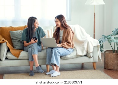 Two woman communicate with their friends and classmates via video link using a laptop and smartphone in the living room. Friends, friendship, time together - Shutterstock ID 2185303771