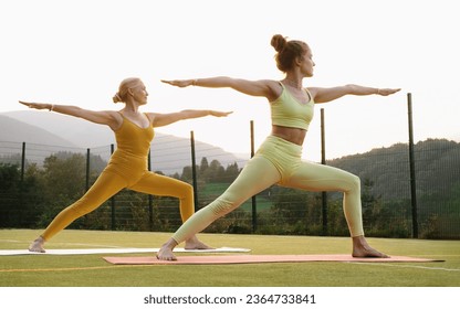 Two woman doing yoga outdoors Mother and adult daughter practicing yoga together. Mature female and young girl having healthy activities. Family Active lifestyle and strength training in mountains - Powered by Shutterstock