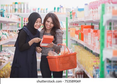 two woman friend buying some stuff at grocery store together - Powered by Shutterstock