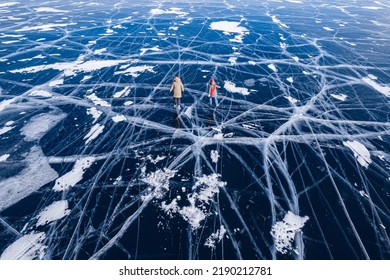 Two Woman Girlfriends Tourists Skate In Winter On Frozen Ice Of Lake Baikal, Aerial Top View.