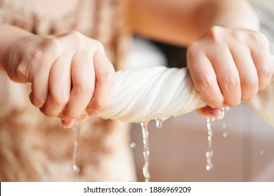 Two woman hands wring wet cloth after washing by twist and squeeze. Housework ,laundry and optimization concept ,selective focus on hand on the left