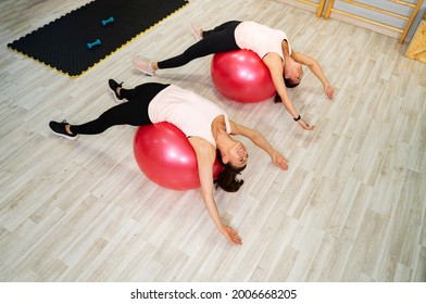 Two Woman Laying On Swiss Balls On Their Back, Back Stretch And Exercise 