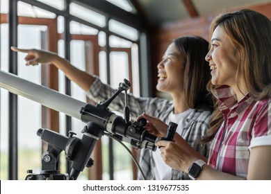 Two Woman Looking Through Binoculars Or Telescope