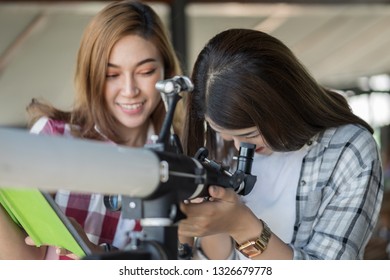 Two Woman Looking Through Binoculars Or Telescope