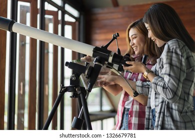 Two Woman Looking Through Binoculars Or Telescope