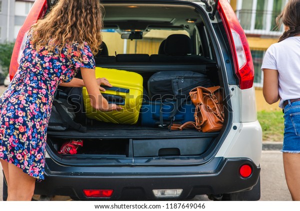two woman\
packing luggage in car trunk. road\
trip