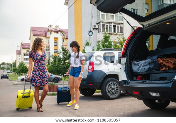 two woman\
packing luggage in car trunk. road\
trip