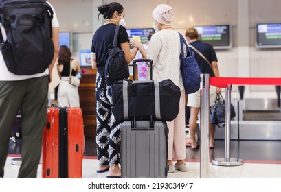 Two woman passengers with face mask check in at the airport - Shutterstock ID 2193034947