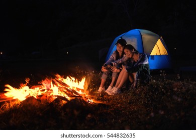 Two woman are sitting around a campfire and just relaxing