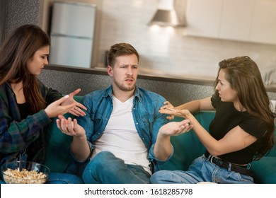 two women arguing with their friend man feeling misunderstanding sitting together on the sofa, opposite sexes concept