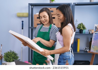 Two women artists standing together looking draw at art studio - Powered by Shutterstock