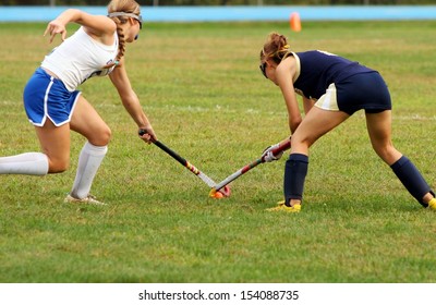 Two Women Battle For Control Of Ball During Field Hockey Game 