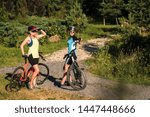 Two women with bikes stopped and have conversation outdoors in the park