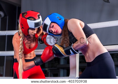 Two  women boxer wearing red  gloves and helmet to box in ring. girls beat each other. Boxing.