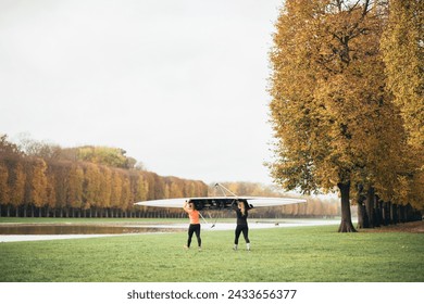 Two women carrying a kayak in the park of the Palace of Versailles in Paris - Powered by Shutterstock