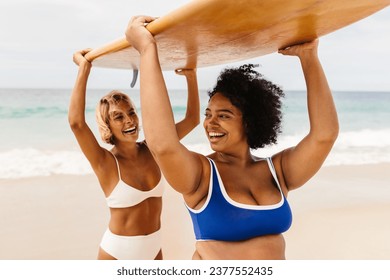 Two women carrying surfboards on a beach, celebrating their friendship and love for water sports. Surfing friends laughing together in bikinis, capturing the essence of a fun-filled summer adventure. - Powered by Shutterstock