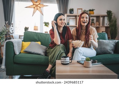 two women caucasian teenage friends or sisters watch movie tv series at home sit on sofa bed with popcorn - Powered by Shutterstock