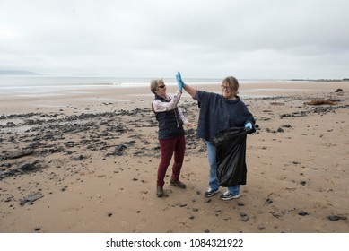 Two women celebrating after picking up rubbish on the beach  - Powered by Shutterstock