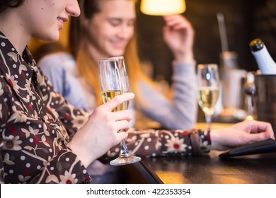 Two women chatting and drinking wine at the bar counter. Blurred peoples on background. - Shutterstock ID 422353354