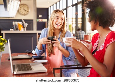 Two Women With Computer Laughing In A Coffee Shop